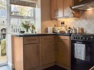 a kitchen with wooden cabinets and a black stove at Church Mouse Cottage in Clitheroe