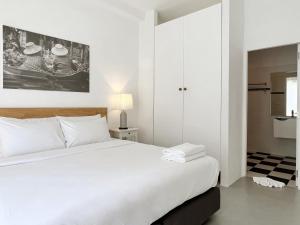 a white bedroom with a large white bed and a door at Isara Khao Lak in Khao Lak