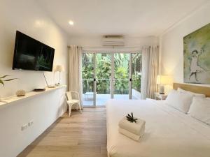 um quarto com uma cama branca e uma porta de vidro deslizante em Isara Khao Lak em Khao Lak