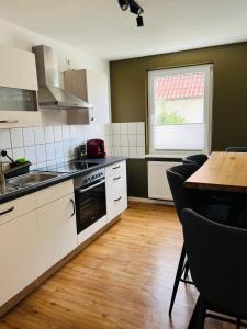 uma cozinha com armários brancos, uma mesa e uma janela em Shadow Sleep em Schonungen
