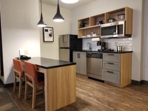a kitchen with a island with a counter and chairs at Candlewood Suites Apex Raleigh Area, an IHG Hotel in Apex