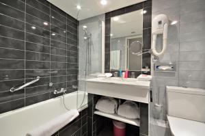 a bathroom with a sink and a tub and a toilet at Cézanne Hôtel Spa in Cannes