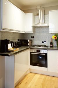 una cocina con armarios blancos y horno negro en Avari Apartments - Winchester Collection en Londres