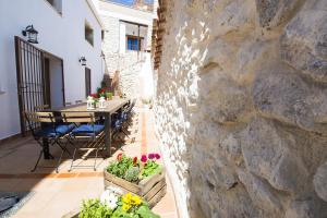een patio met een tafel en stoelen en een stenen muur bij Casa Rural Valle de la Laguna in Valdelaguna