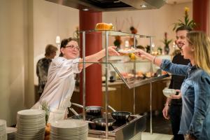 a woman holding a plate in front of a buffet at Hotel Esplanade Resort & Spa - Adults Only in Bad Saarow