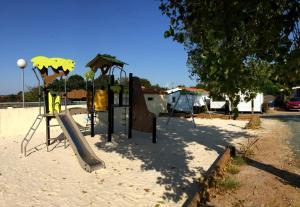 un parque infantil con un tobogán en la arena en Camping Le Bellevue en La Tranche-sur-Mer