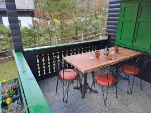 Holiday home Pri Metki - Bohinj في بوينج: طاولة وكراسي خشبية على شرفة مع باب أخضر