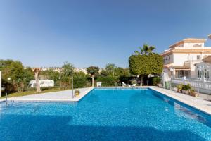 a swimming pool with blue water in front of a house at Espanatour PLAYA FLAMENCA in Orihuela Costa