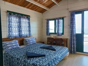 a bedroom with a bed and a table and windows at The Nest Palolem in Canacona