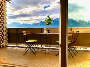 een tafel en stoelen op een balkon met uitzicht op de bergen bij Central Studio with Lake View | 102 in Montreux