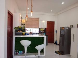 a kitchen with two white stools and a green counter at Kurulu Villa Hikkaduwa in Gonapinuwala West