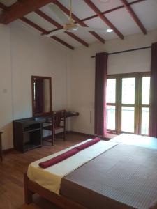 a bedroom with a bed and a desk and window at Villa 95 Rangala in Kandy