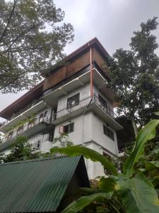 a tall white building with a wooden roof at Villa 95 Rangala in Kandy