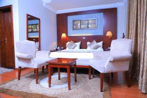 een slaapkamer met een bed en 2 stoelen en een tafel bij Sidra International Hotel in Addis Ababa