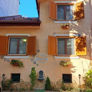 a building with orange shutters and a sign on it at Villa Magicland in Sofia