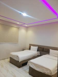 two beds in a room with purple lights on the ceiling at المغتره للشقق الفندقيه in Ad Dawādimī