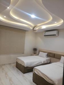 una camera d'albergo con due letti e un soffitto di المغتره للشقق الفندقيه ad Ad Dawādimī
