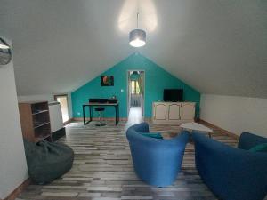 - un salon avec des chaises bleues et un piano dans l'établissement Les Mansardes l'Appart, à Sarlat-la-Canéda