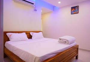 - un lit avec des draps et des oreillers blancs dans l'établissement Priya Woodz Homestay, Tirupati, à Tirupati