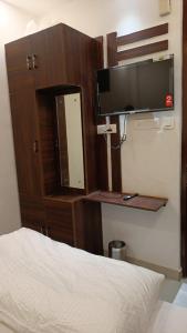 1 dormitorio con 1 cama y TV en la pared en Hotel Cross Road By WB Inn en Unnāo