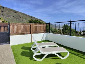 a white lounge chair on a balcony with grass at Sunset las hadas in Candelaria