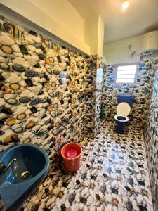 a bathroom with a toilet and a sink with a mosaic wall at Venish Home Stay in Kodaikānāl