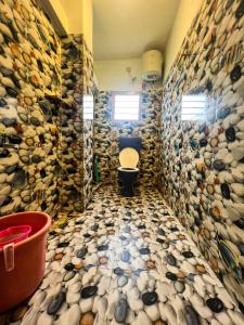 a bathroom with a toilet and a wall of rocks at Venish Home Stay in Kodaikānāl