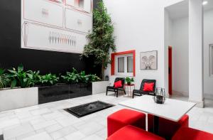 - un salon avec une table blanche et des chaises rouges dans l'établissement Hotel Del Pintor, à Malaga