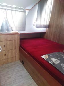 uma cama num pequeno quarto com uma janela em BATEAU - Jolie pénichette sur région touristique. em Bellegarde