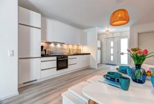 a kitchen with white cabinets and a white table at Bernsteinquartier BQ 9c Ostseenest in Kolpinsee
