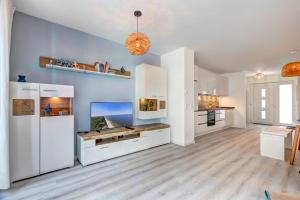 a large kitchen with white cabinets and a blue wall at Bernsteinquartier BQ 9c Ostseenest in Kolpinsee