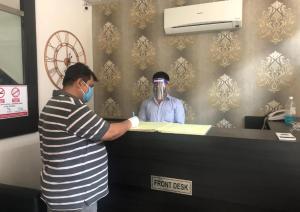 a man in a mask standing at a front desk at Banani Resort By WB Inn in Gosāba