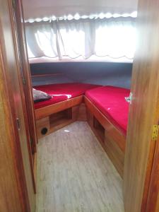 ein kleines Zimmer mit einem roten Bett auf der Rückseite in der Unterkunft BATEAU - Jolie pénichette sur région touristique. in Bellegarde