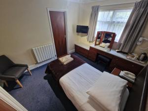 a bedroom with a bed and a mirror and a chair at Grange Lodge Hotel in Saint Peter Port
