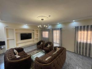 a living room with two couches and a tv at Maison d'Hôtes entière Cité Douane Golf Dakar in Dakar