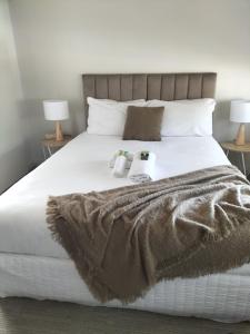 a white bed with two towels and two lamps on it at Normandie Wollongong in Wollongong