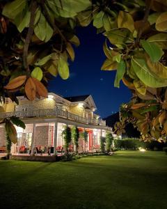 una grande casa con luci su un prato di notte di Karan Mahal a Srinagar