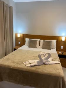 Hotel Portal do Descobrimento في بورتو سيغورو: مناشف بجعتين على سرير في غرفة الفندق