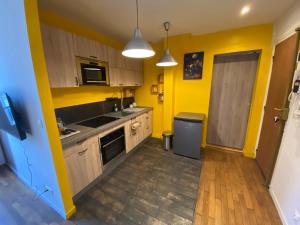 uma cozinha com paredes amarelas e armários de madeira em Superbe T2 entre Paris et Disney (RER A) em Nogent-sur-Marne
