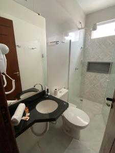 a bathroom with a sink and a toilet and a shower at Hotel Portal do Descobrimento in Porto Seguro