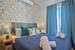 een slaapkamer met een blauw bed met een handdoek erop bij Tower Road - Central Sliema Modern Apartments and Duplex Penthouse by ShortletsMalta in Sliema