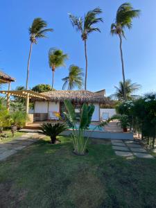 una casa con palmeras delante en Tiki Pool's Bungalows en Fortim