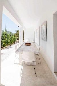 a white dining room with a table and white chairs at Balinese Villa near the beach outdoor jacuzzi in Cala Llonga