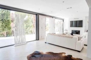 a living room with a white couch and large windows at Balinese Villa near the beach outdoor jacuzzi in Cala Llonga