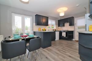 a kitchen with black cabinets and a table and chairs at Signature - Carnbroe House in Old Monkland