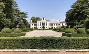 une grande maison blanche avec un jardin et des arbres dans l'établissement Foresteria Di Villa Tiepolo Passi, à Trévise