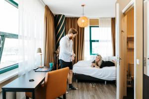 a man standing in a hotel room with a woman on a bed at The Hague Teleport Hotel in The Hague