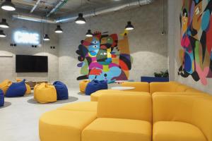 a waiting room with yellow couches and a mural at Micampus San Mamés Students Residence in Bilbao