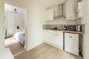 uma cozinha com armários brancos e uma cama num quarto em Terrasse des Loges em Rennes