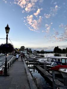 a dock with boats docked on a river with a cloudy sky at 15th century tiny character cottage-Henley centre in Henley on Thames